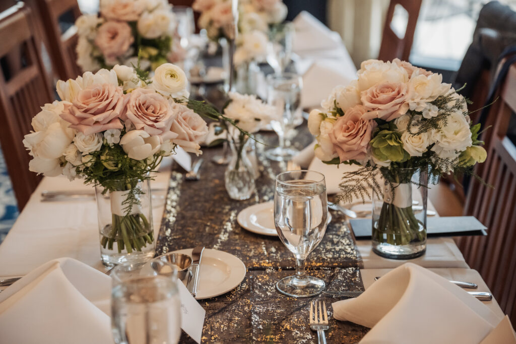 Wedding table decor: light pink and white rose bouquets and full dinnerware spread